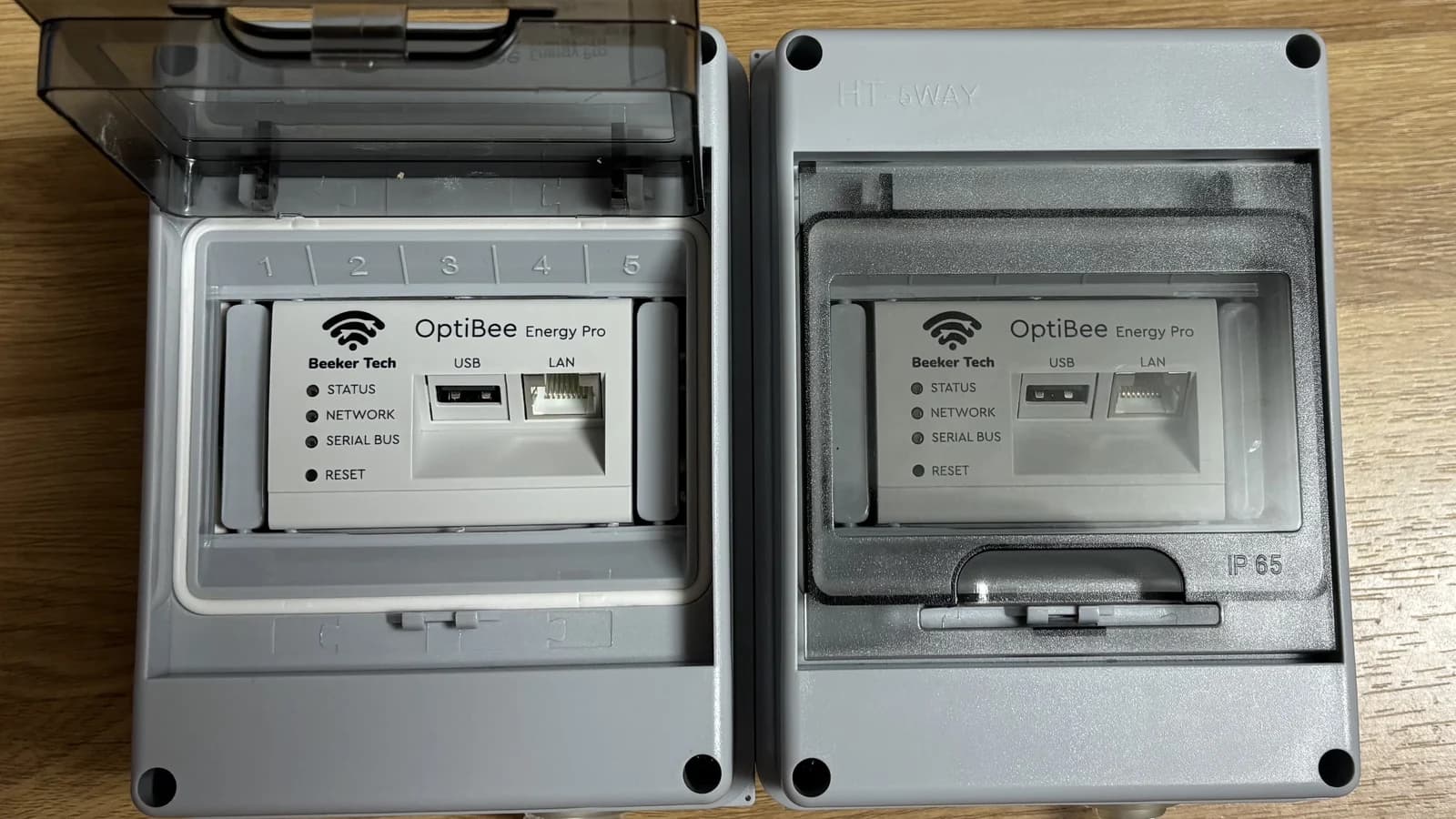 Two OptiBee Energy Pro units in IP65 enclosures on a workbench, one lid open.